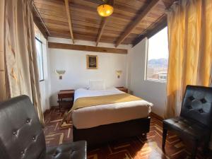 a bedroom with a bed and a chair and a window at Cusco Golden Perú Inn in Cusco