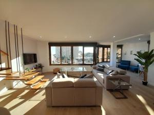 ein großes Wohnzimmer mit einem Sofa und einem TV in der Unterkunft Costa Blanca Holiday Rental AltaMar I in El Campello