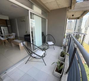 uma varanda com duas cadeiras e uma mesa num edifício em Apartamento 2 Ambientes - Moderno totalmente Amoblado em Buenos Aires