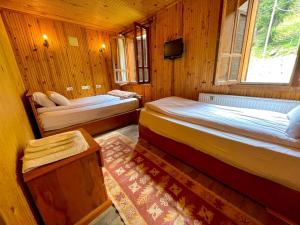 a bedroom with two beds and a tv in a room at Ayder Vesile Otel in Ayder Yaylasi