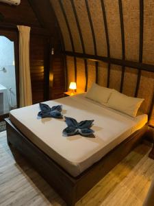 a bed with two blue flowers on it at Gili Davidoff Bungalow in Gili Trawangan