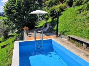 a blue swimming pool with an umbrella and a chair at Schwendi-Blueme in Heiligenschwendi