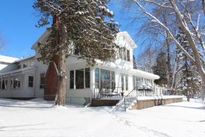 a white house with snow on the ground at Tally Ho Inn in Huntsville