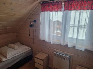 Kleines Zimmer mit einem Bett und einem Fenster in der Unterkunft Domki na Zagroniu in Koninki