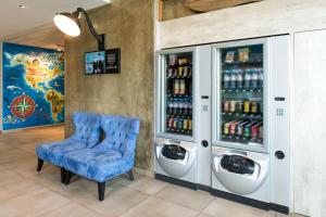 um quarto com uma cadeira azul e máquinas de refrigerantes em ibis budget Aéroport Lyon Saint Exupéry em Saint-Exupéry
