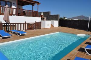 a swimming pool with two chairs and a house at Villa Esmeralda in Playa Blanca