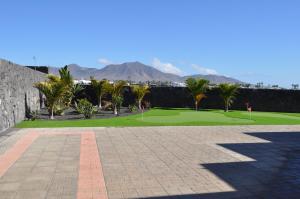 a golf course with palm trees and a stone wall at Villa Esmeralda in Playa Blanca