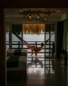 a man sleeping in a hammock in a living room at Seven Blue House Village & Lodge in Bacalar