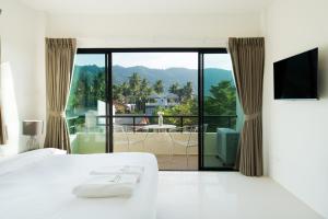 a bedroom with a bed and a view of a balcony at Hill Myna Holiday Park & Cafe in Bang Tao Beach
