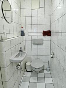 La salle de bains est pourvue de carrelage blanc, de toilettes et d'un lavabo. dans l'établissement Ferienwohnung Wanderparadies Neuwied-Heimbach, à Neuwied