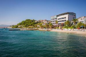 a beach with a group of people in the water at Apartments Solmar in Podstrana