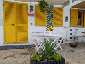 biały stół i krzesła przed budynkiem z żółtymi drzwiami w obiekcie Serra da Estrela Guest House w mieście Covilhã