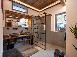 a bathroom with a glass shower and a wooden ceiling at das brunn - Luxus Chalet in Kirchberg in Tirol