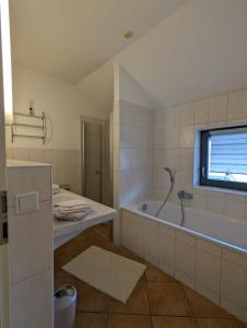 baño con bañera, lavabo y ventana en Ferienhaus Ketterer Hinterzarten, en Hinterzarten