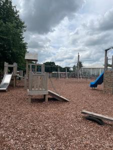 a playground with two swings and a slide at Holiday home at cherry tree holiday park Burgh castle Great Yarmouth Norfolk in Great Yarmouth