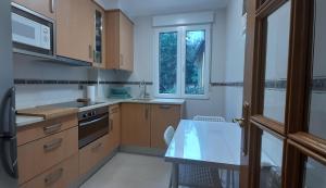 a kitchen with wooden cabinets and a table and a window at Piso centro Santander - Parking Gratuito in Santander