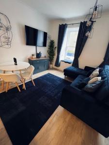 a living room with a black couch and a table at Modern Town-Centre Apartment in Dumfries