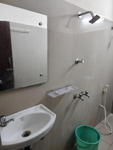 a bathroom with a sink and a mirror and a bucket at Raja Rani Mahal Ac-Rooms in Tiruvannāmalai