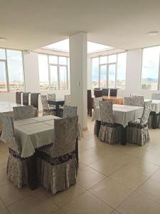 uma sala de jantar com mesas, cadeiras e janelas em D´Milez Hotel em Puerto Maldonado