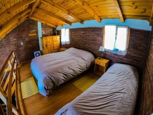 a bedroom with two beds and a brick wall at Cabañas Patagonia Rupestre in El Bolsón
