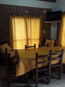 a dining room table and chairs with a yellow curtain at La Loma Resort in Merlo