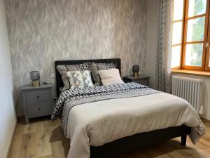 ein Schlafzimmer mit einem Bett mit zwei Nachttischen und zwei Fenstern in der Unterkunft Maison rénovée au cœur du Haut-Jura in Entre-Deux-Monts