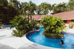 una mujer nadando en una piscina con palmeras en Mawamba Lodge, en Tortuguero