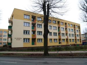 un bâtiment jaune avec un arbre devant lui dans l'établissement Mieszkanie 3 pokojowe Park Chopina, à Świnoujście