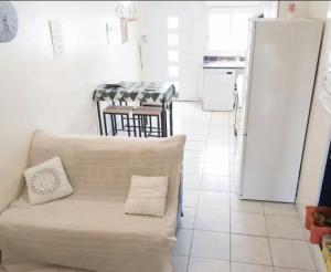 a living room with a white couch and a kitchen at T1 proximité de Montpellier. in Juvignac