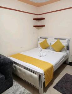 sypialnia z białym łóżkiem z żółtymi poduszkami w obiekcie Spacious studio near highway w mieście Kinoo