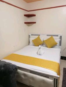 sypialnia z łóżkiem z żółtymi i białymi poduszkami w obiekcie Spacious studio near highway w mieście Kinoo