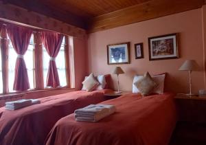 two beds in a room with pink walls and windows at FLOR AUSTRAL in Ushuaia