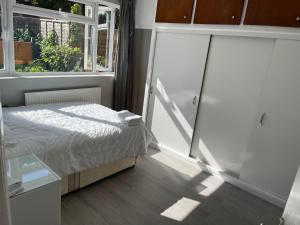 a bedroom with a bed and a window at Entire Lovely 2 bedroom apartment with private garden & free street parking in London