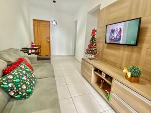 - un salon avec un canapé et un arbre de Noël dans l'établissement F034 - Apto no Forte Churrasqueira, Wi-Fi e Piscina, à Praia Grande