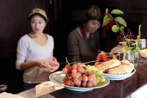 Kominka Washinkan - Vacation STAY 13791 في Yaita: سيدتان واقفتان على طاولة مع أطباق من الطعام