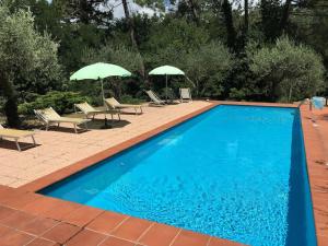 a swimming pool with two umbrellas and chairs at Podere La Cerraia in Serravalle Pistoiese
