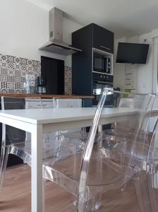 uma mesa branca com cadeiras de plástico transparente numa cozinha em Gîte Mont Saint Michel Beauvoir em Beauvoir