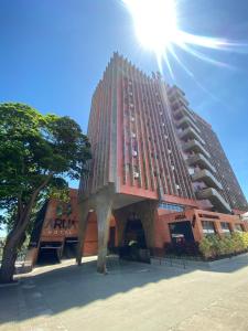 um edifício de tijolos altos com o sol no céu em Aruá Hotel em Presidente Prudente