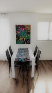 einen weißen Esstisch mit Stühlen und ein Gemälde in der Unterkunft L'Escale n°5 in Tartas