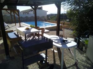 einen Tisch und Stühle unter einem Sonnenschirm neben einem Pool in der Unterkunft Casa rural CAÑADA PAEZ in Vélez-Málaga