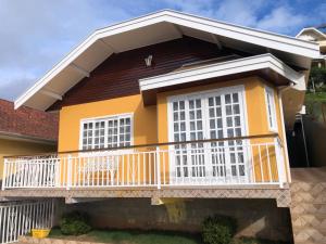 een geel huis met een wit balkon bij Sonho Meu in Campos do Jordão