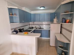 La cuisine est équipée de placards bleus et d'un réfrigérateur blanc. dans l'établissement Monte Mar Apartment, à Gran Alacant