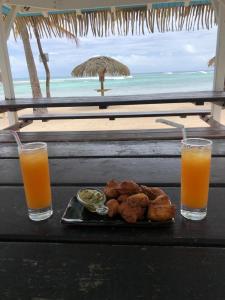a table with a plate of food and two glasses of orange juice at Studio TY SOLEY in Saint-François
