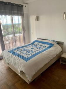 a bed with a blue and white quilt on it at Vence T3 vue mer grande terrasse in Vence