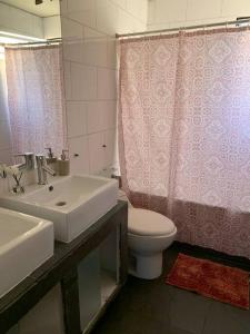 y baño con lavabo, aseo y cortina de ducha. en Agradable casa con piscina, cerca del mall. en Santiago