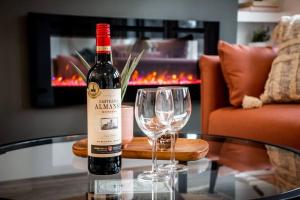 a bottle of wine and two wine glasses on a table at Chic Retreat, 4BR Near DT & WEM, Fireplace, Trails, Sleeps 10! in Edmonton