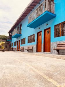 a blue building with wooden doors and a balcony at Residencial Albatroz in Caraguatatuba