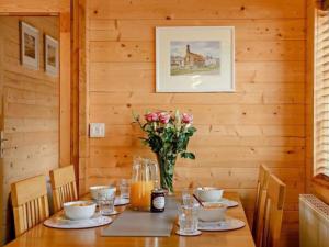 una mesa de madera con un jarrón de flores. en Hulver Lodge, Snape, Suffolk., en Snape