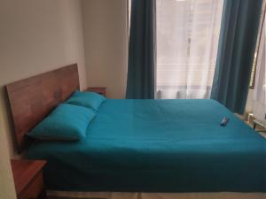 ein Schlafzimmer mit einem Bett mit blauen Laken und einem Fenster in der Unterkunft Depto Condominio La Casona in El Quisco