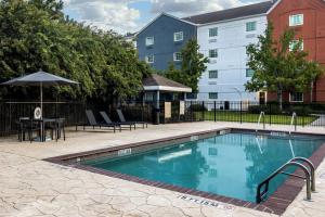 een zwembad met een tafel en stoelen en een gebouw bij Candlewood Suites - Bluffton-Hilton Head, an IHG Hotel in Bluffton